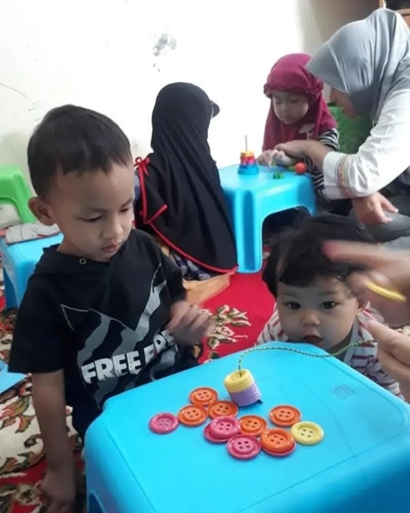 Anak belajar dengan permainan tombol warna di meja kecil