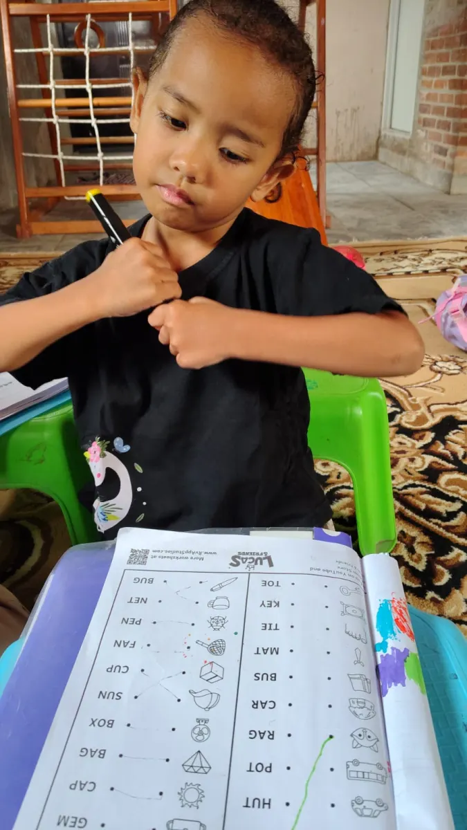 Anak mengerjakan worksheet dengan fokus